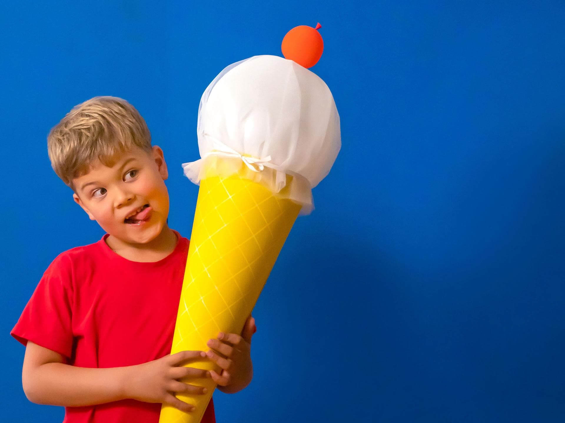 Ein kleiner Junge, der eine selbstgebastelte Eis-Schultüte in der Hand hält. Ein kleiner Junge, der eine selbstgebastelte Eis-Schultüte in der Hand hält.