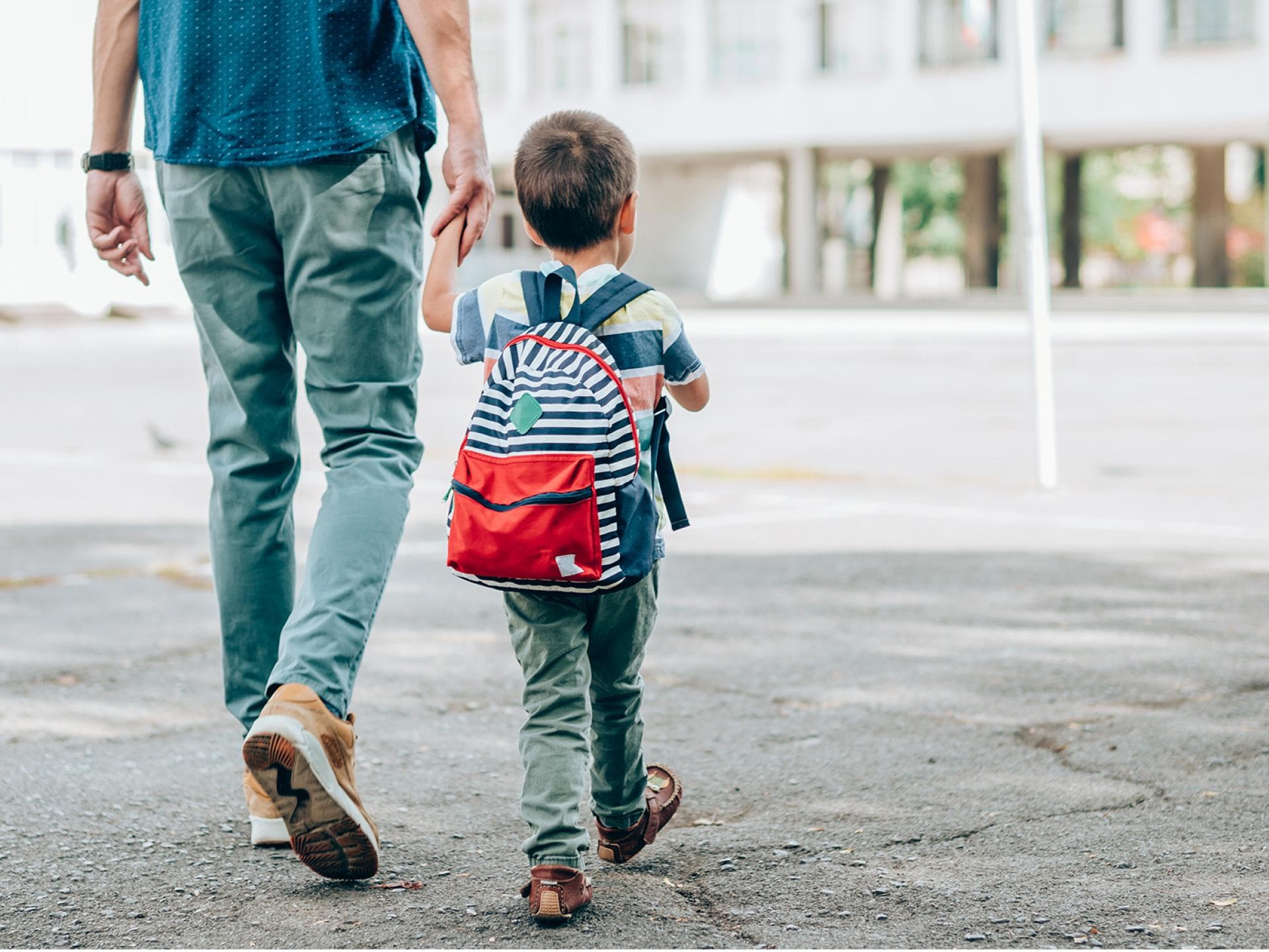 Was Kinder vor der Einschulung können müssen. Vater geht mit kleinem Kind an der Hand zur Schule.