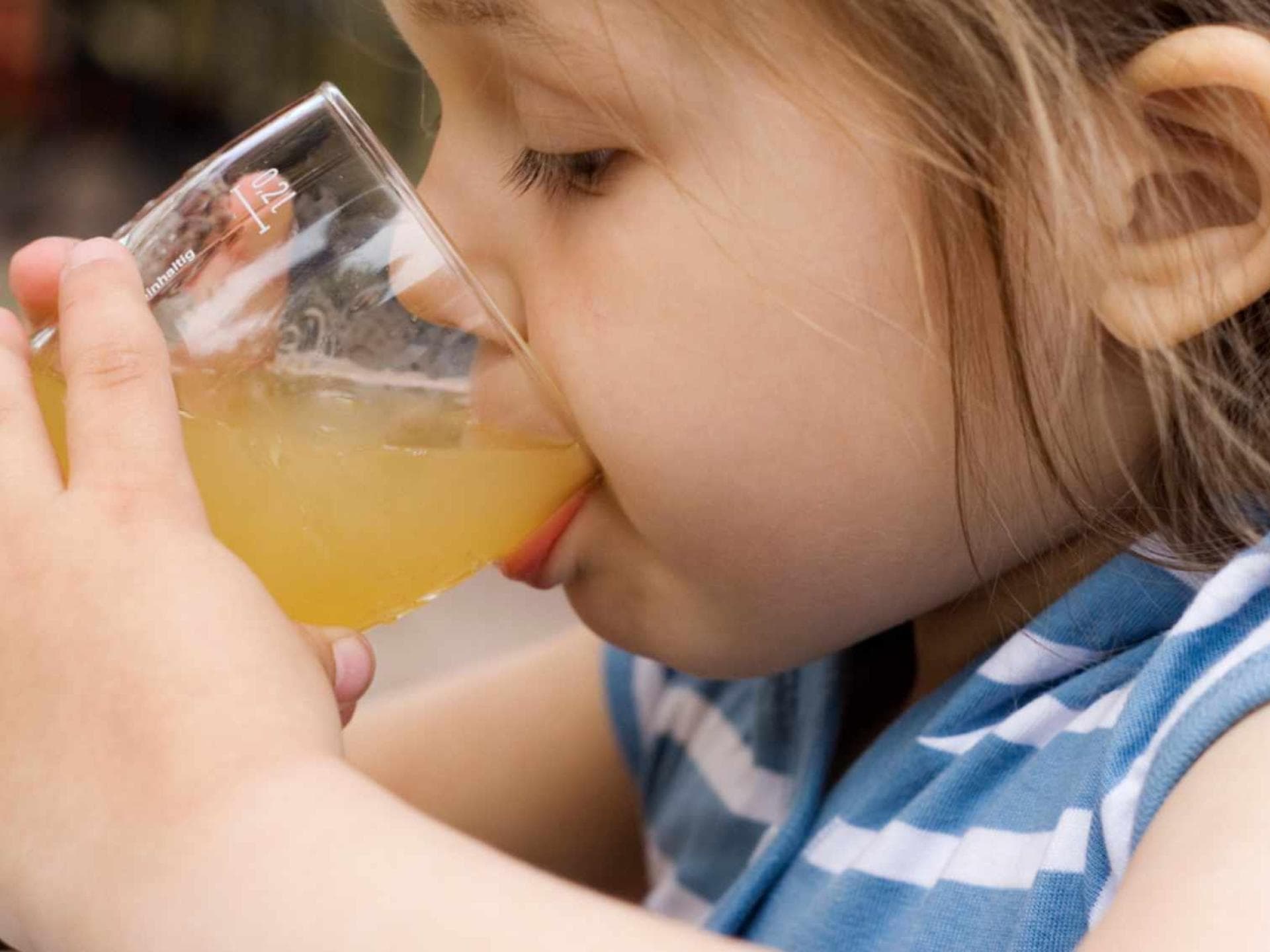 Kind trinkt Apfelsaft aus einem Glas.