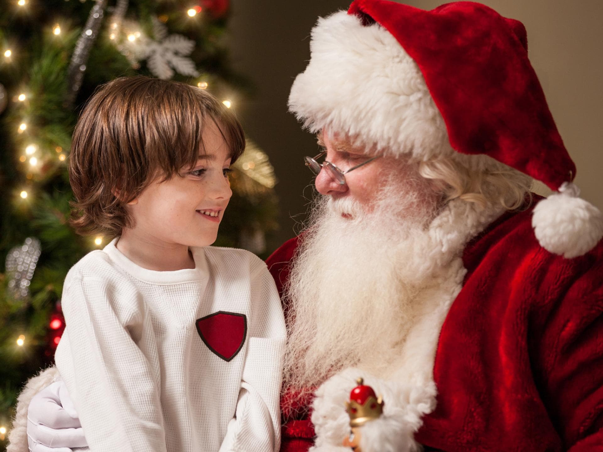 Kind sitzt auf dem Schoß vom Nikolaus oder Weihnachtsmann.