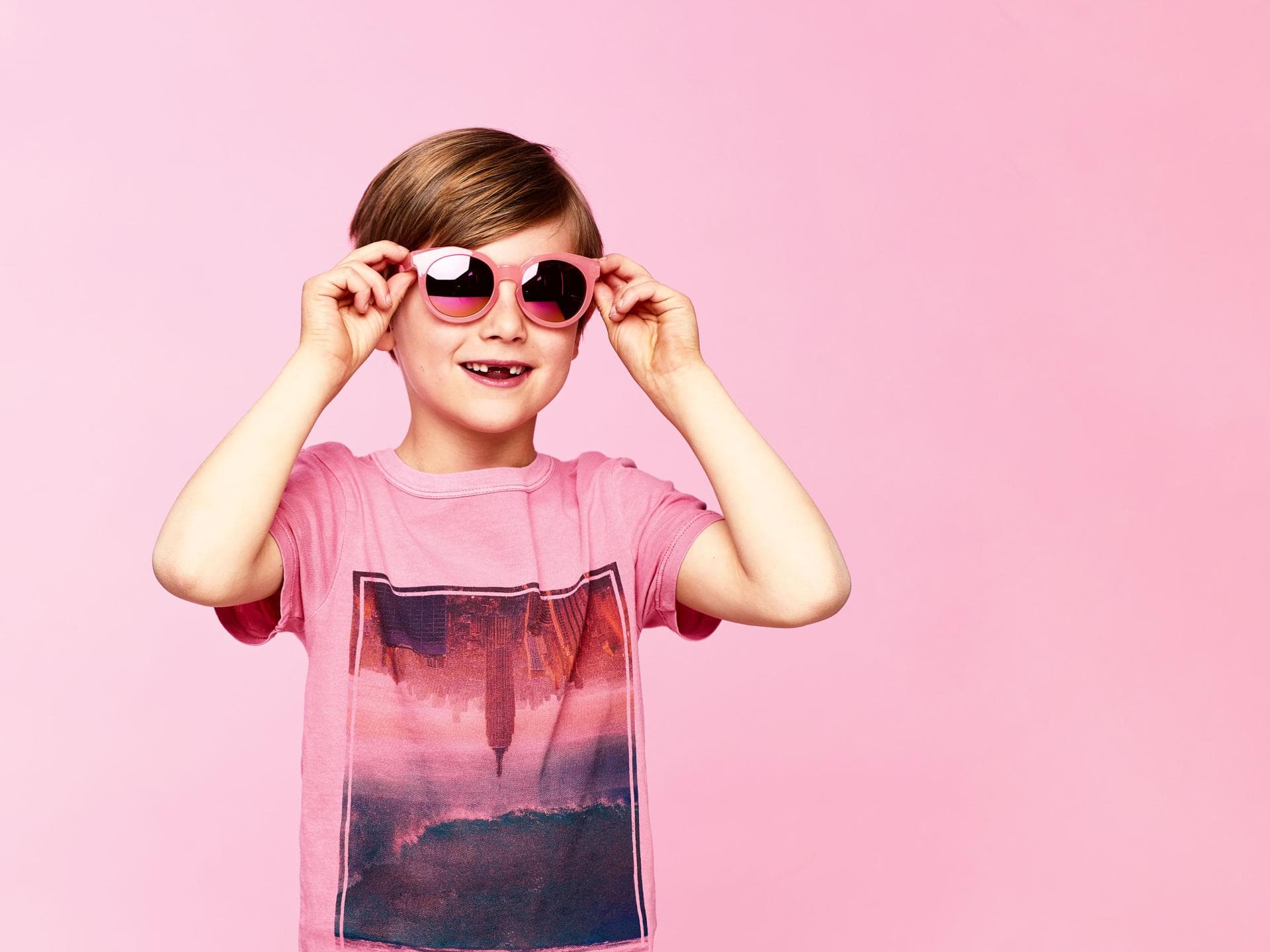 Junge mit rosa T-Shirt und rosa Sonnenbrille.