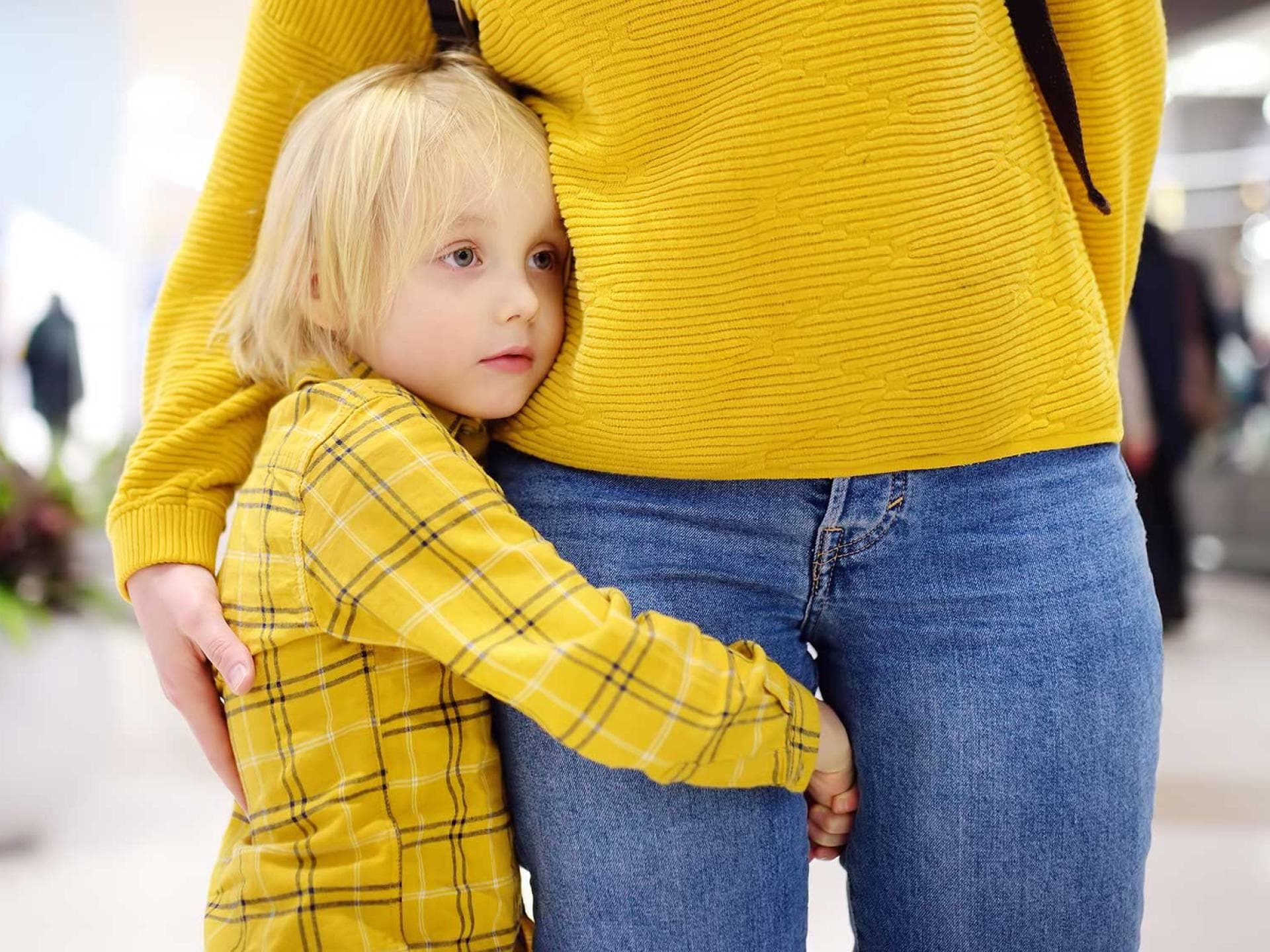 Nicht ohne meine Mama! Kind umarmt das Bein seiner Mama, um ganz nah bei ihr zu sein