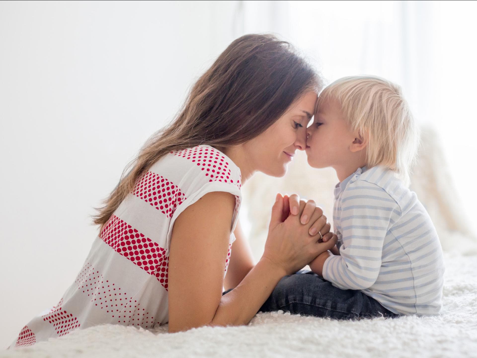 Gute-nacht-Gebete können Kindern am Abend Sicherheit geben. Mutter und Kind beten gemeinsam.