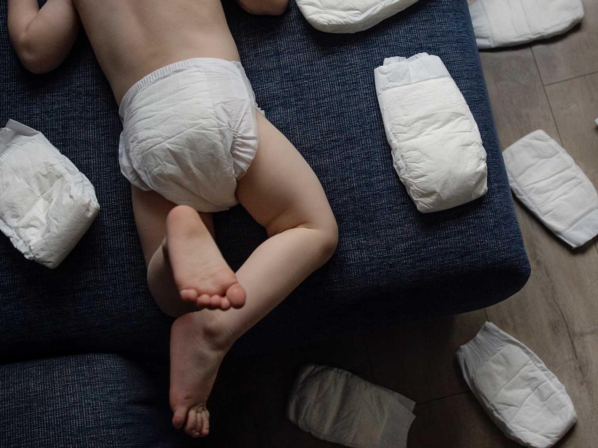 Wer kennt's? Es mieft, aber das zweijährige Kleinkind hat null Bock auf eine neue Windel ... Kleinkind mit Windelpo zwischen Windeln.