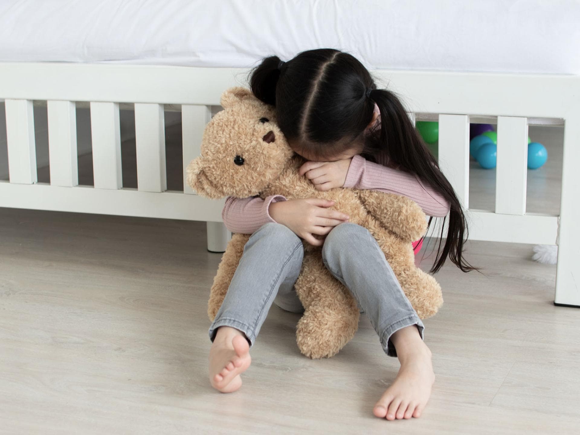 Kind hat Heimweh und weint in seinen Teddy.