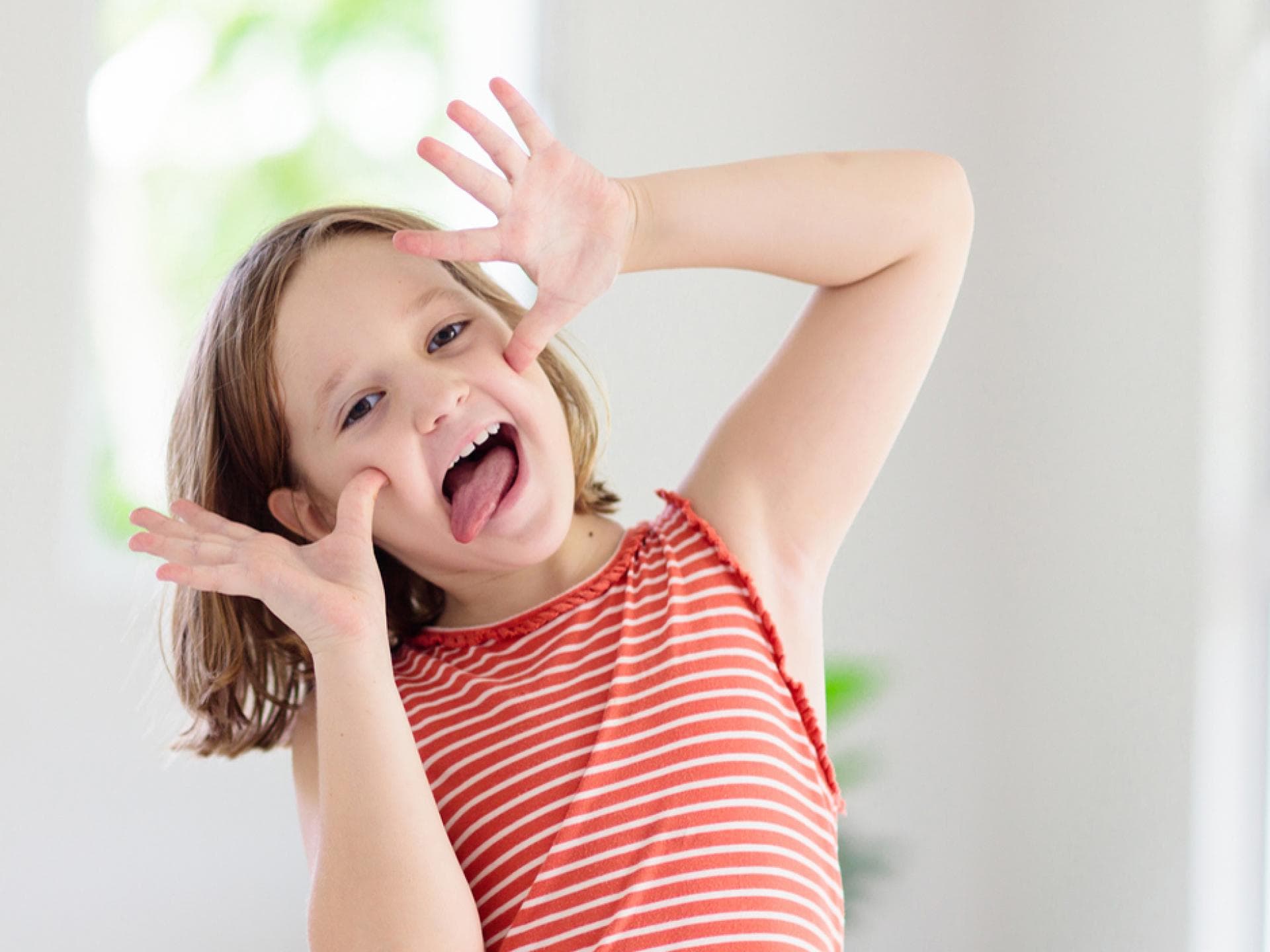 Lachen und Quatsch machen geht immer ... Dabei entwickelt sich der Humor von Kindern weiter. Kind schneidet eine Grimasse.