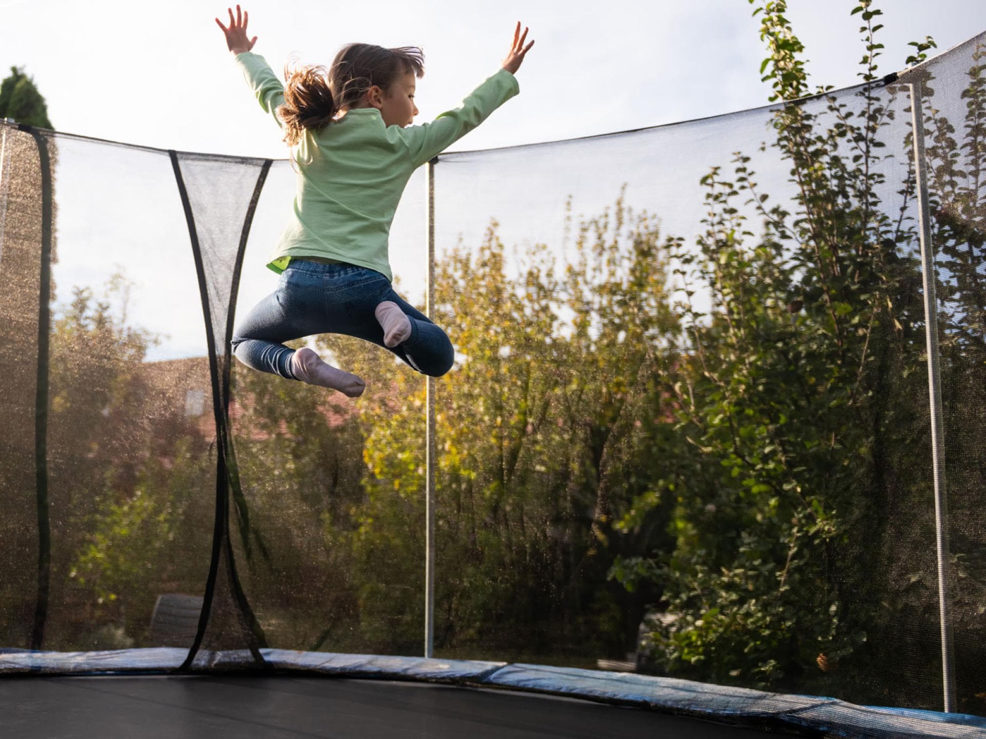 Trampolinspringen ist nicht ungefährlich. Die Kleinen sollten einige Dinge dabei beachten. Kind springt hoch auf rundem Trampolin.