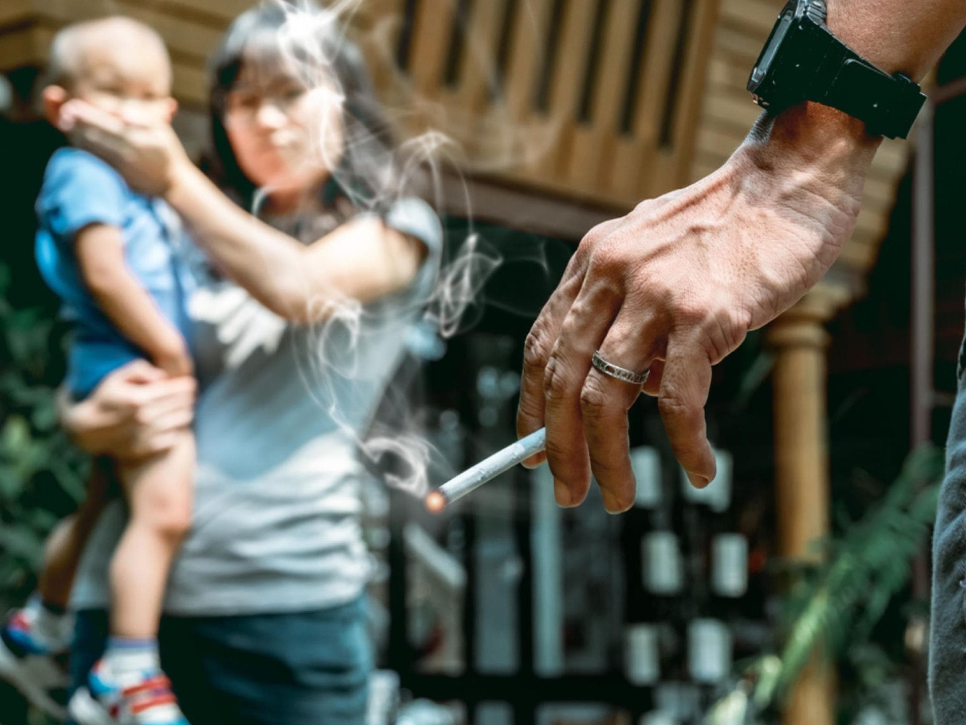 Wenn Großeltern im Beisein eines Babys rauchen, führt das häufig zu Streit. Eine Oma raucht vor einem Baby. Die Mutter hält ihm den Mund zu.