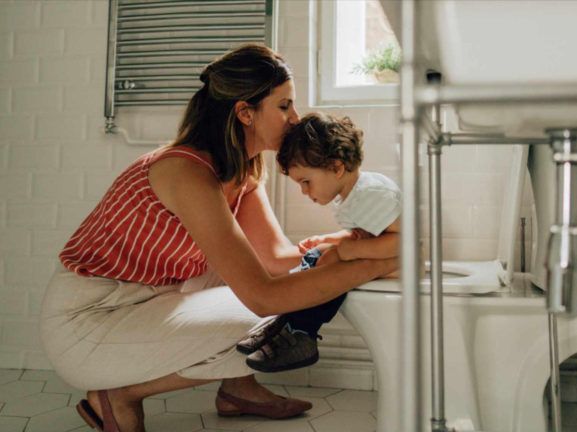 Mutter begleitet Kleinkind auf die Toilette.