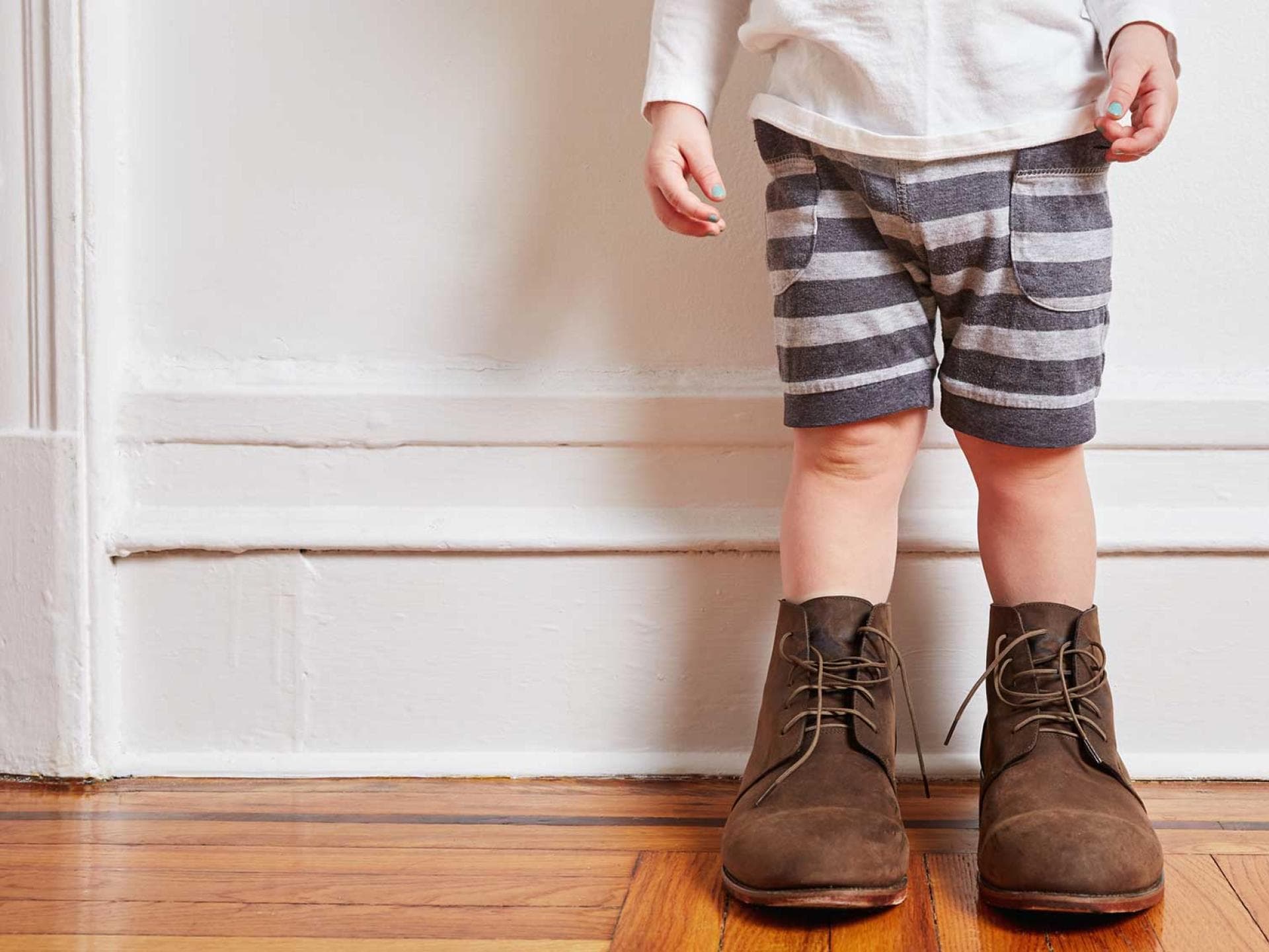 Kleinkind mit viel zu großen Schuhen.