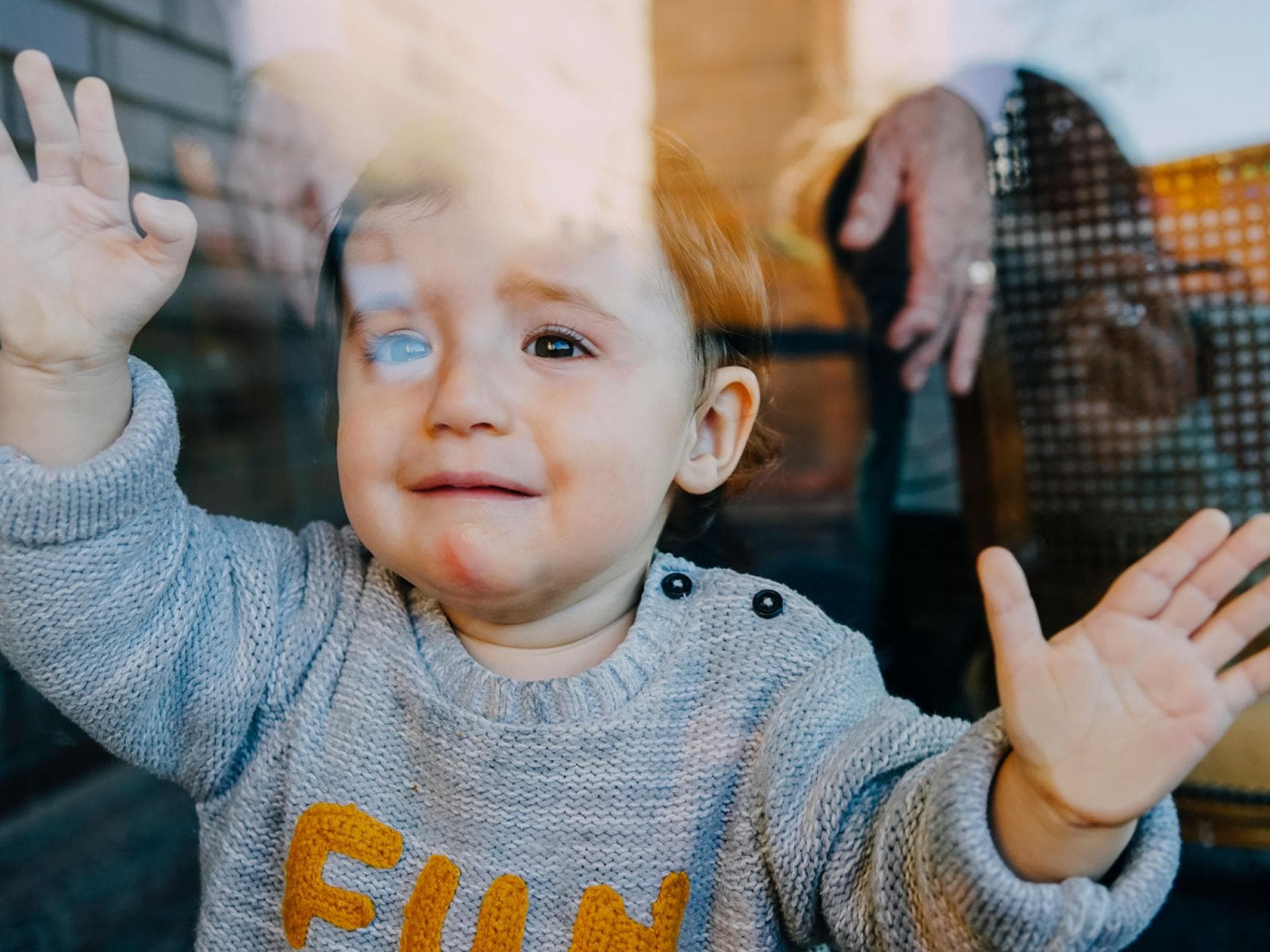 Fremdbetreuung in der Kita kann für kleine Kinder tatsächlich schädlich sein. Kleinkind hinter der Scheibe weint beim Abschied.