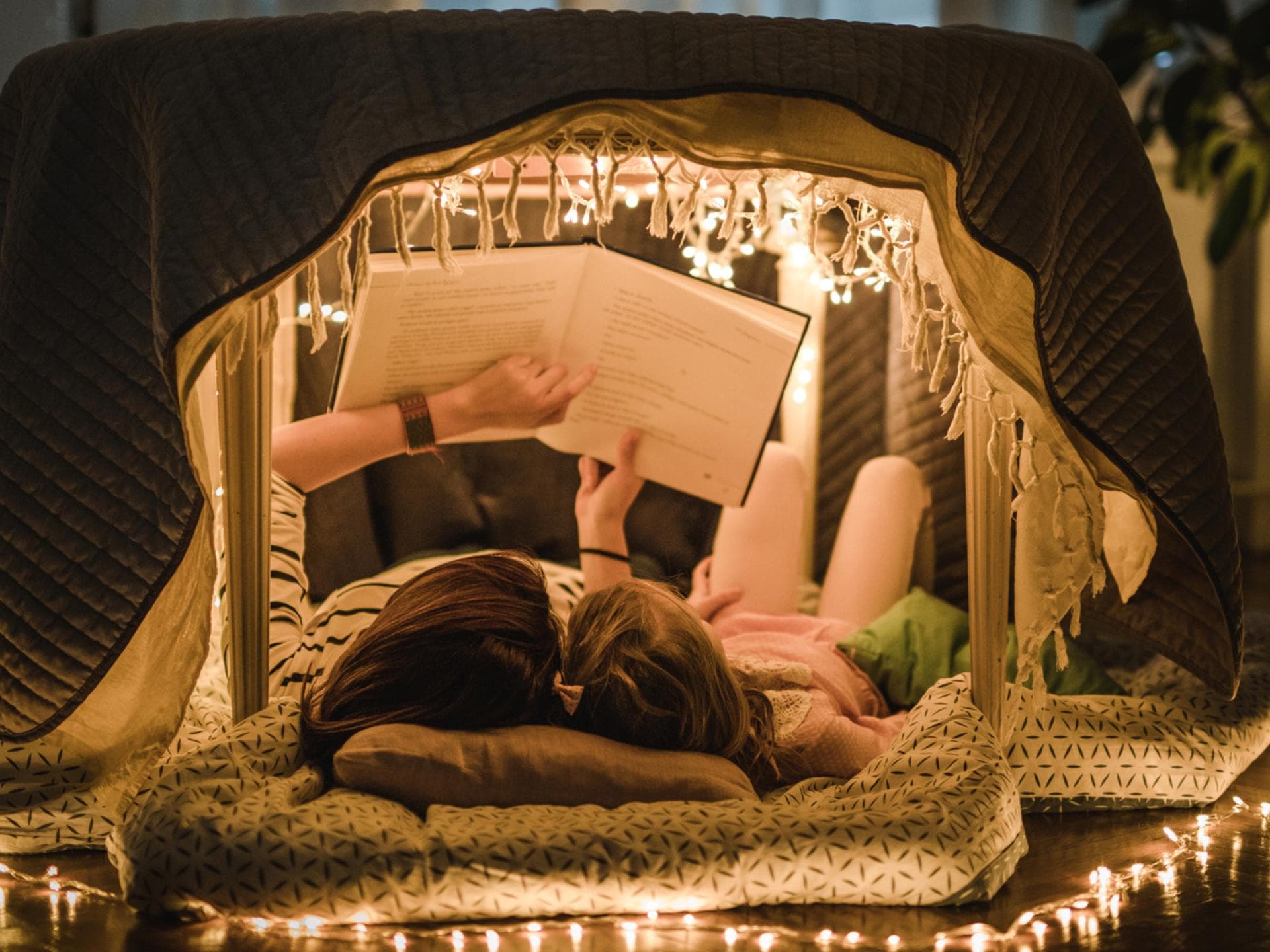 Mutter und Kind lesen Märchen in einer Höhle in der Wohnung.