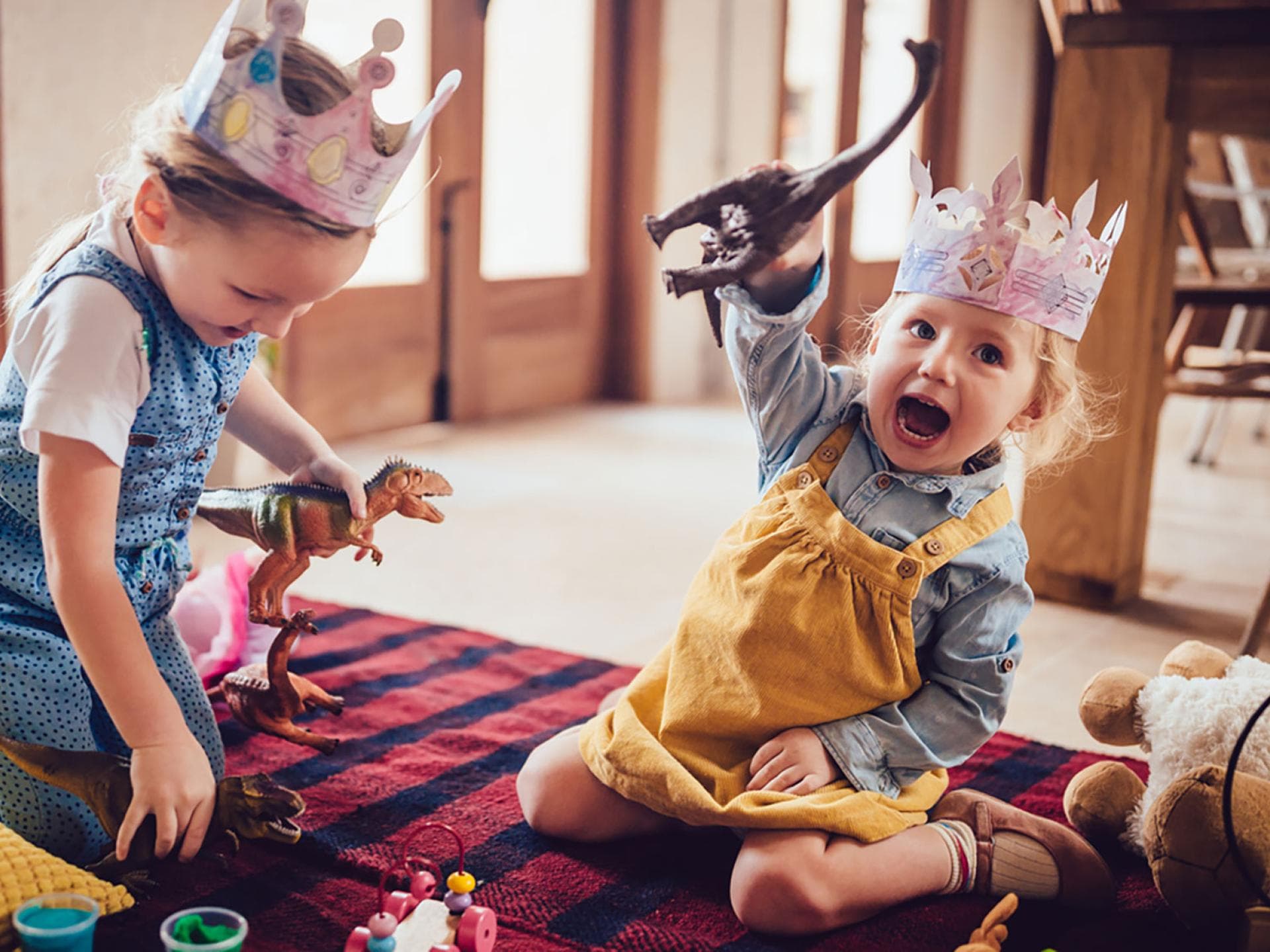 Zwei kleine Kinder spielen mit Dino-Figuren.