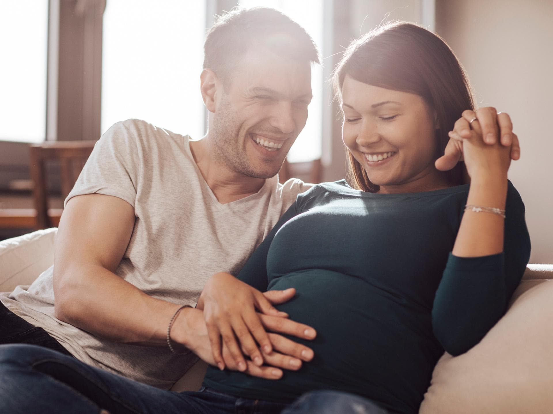 Paar streichelt den Babybauch.