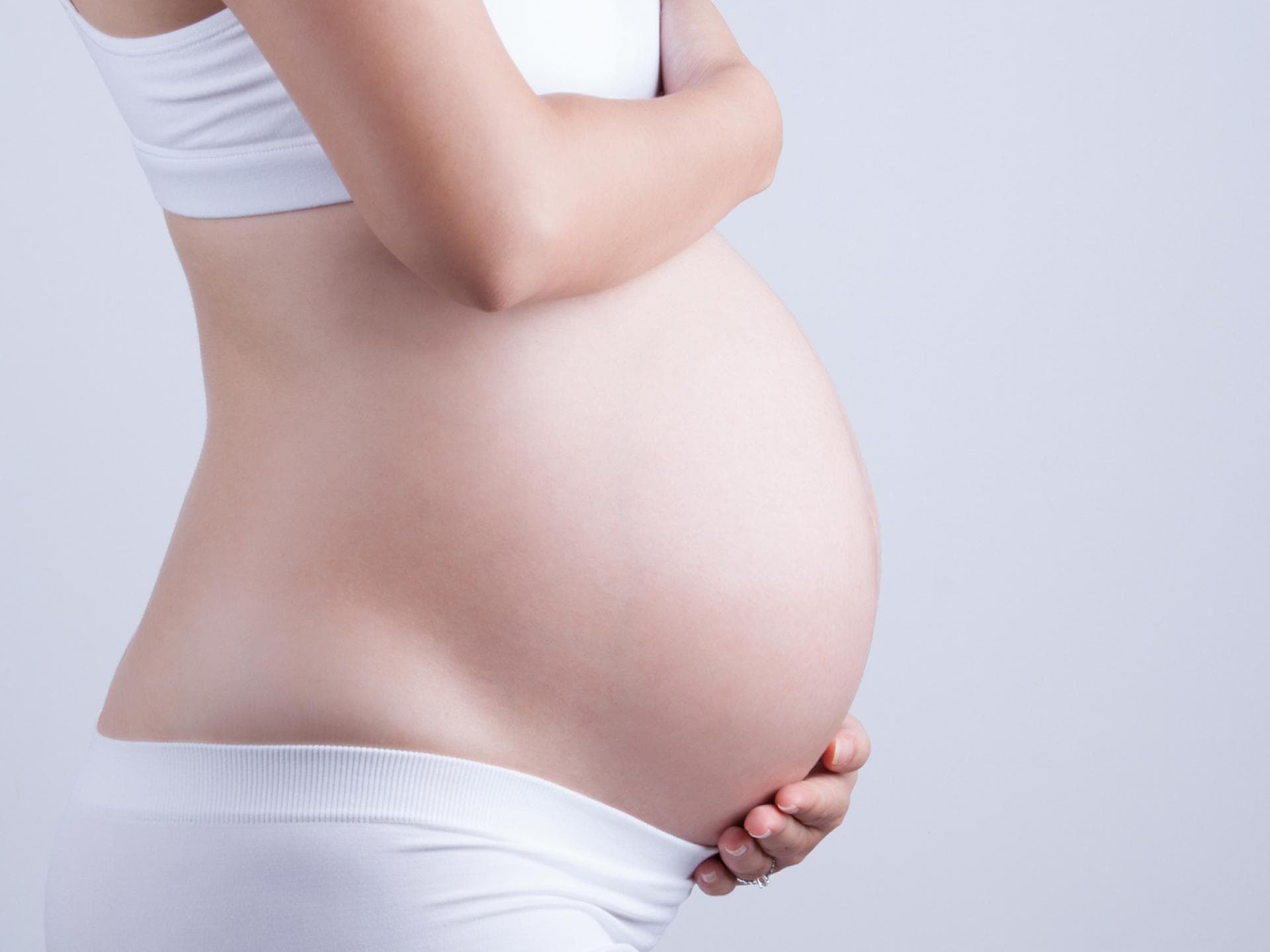 Übungen wie der Kniehocker oder die Knie-Ellenbogen-Lage helfen, das Ungeborene in die richtige Position für die Geburt zu drehen. Bauch einer Schwangeren