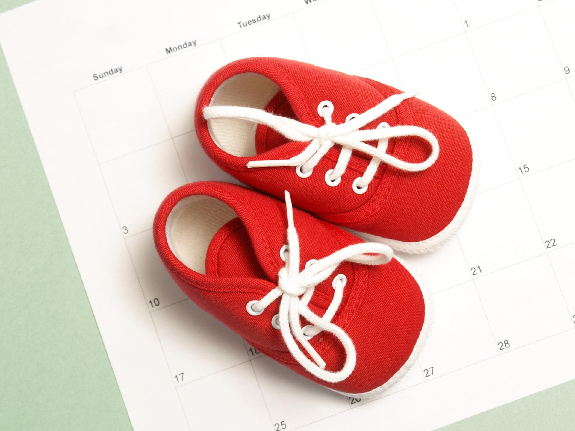 Der errechnete Geburtstermin stimmt nur bei drei Prozent aller Kinder. Babyschühchen auf einem Kalender.