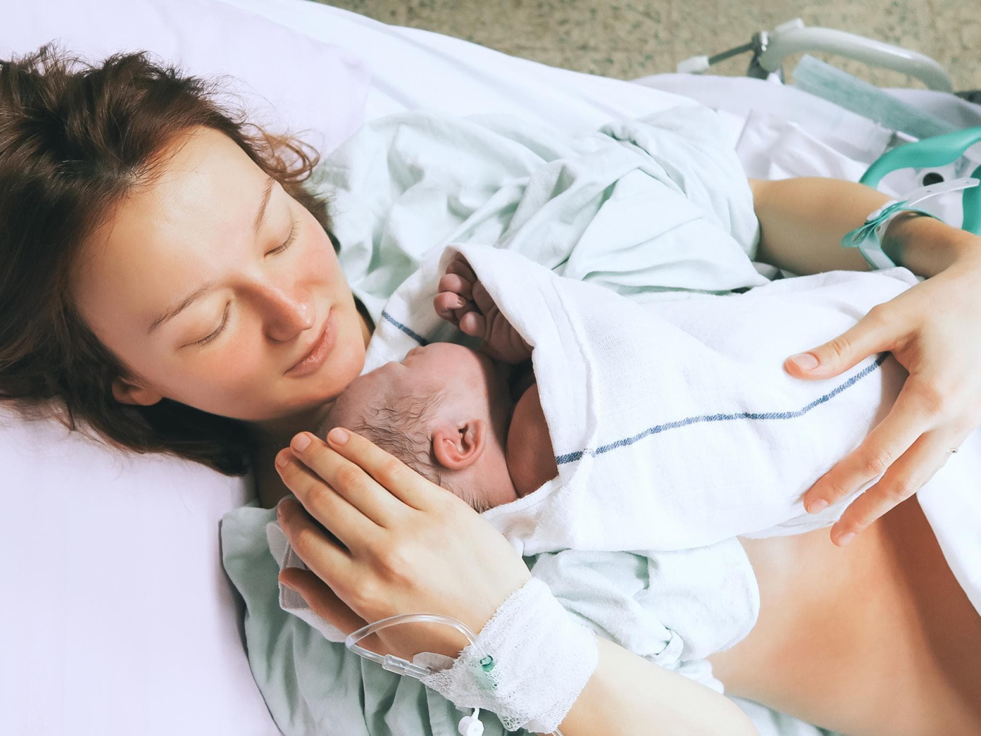 Neugeborenes liegt auf Mamas Oberkörper.