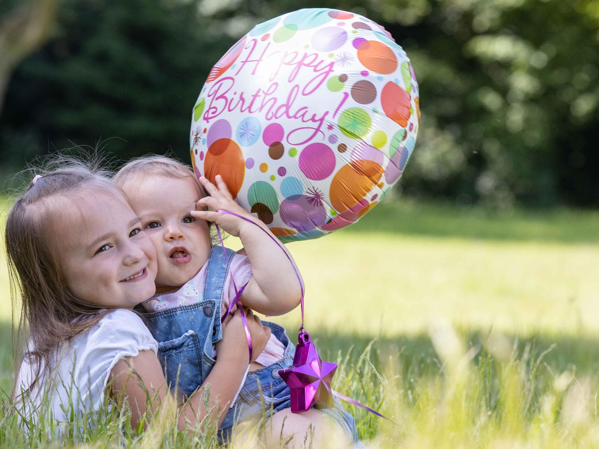 Die zwei Schwestern haben am selben Tag Geburtstag. Geschwister mit Luftballon.