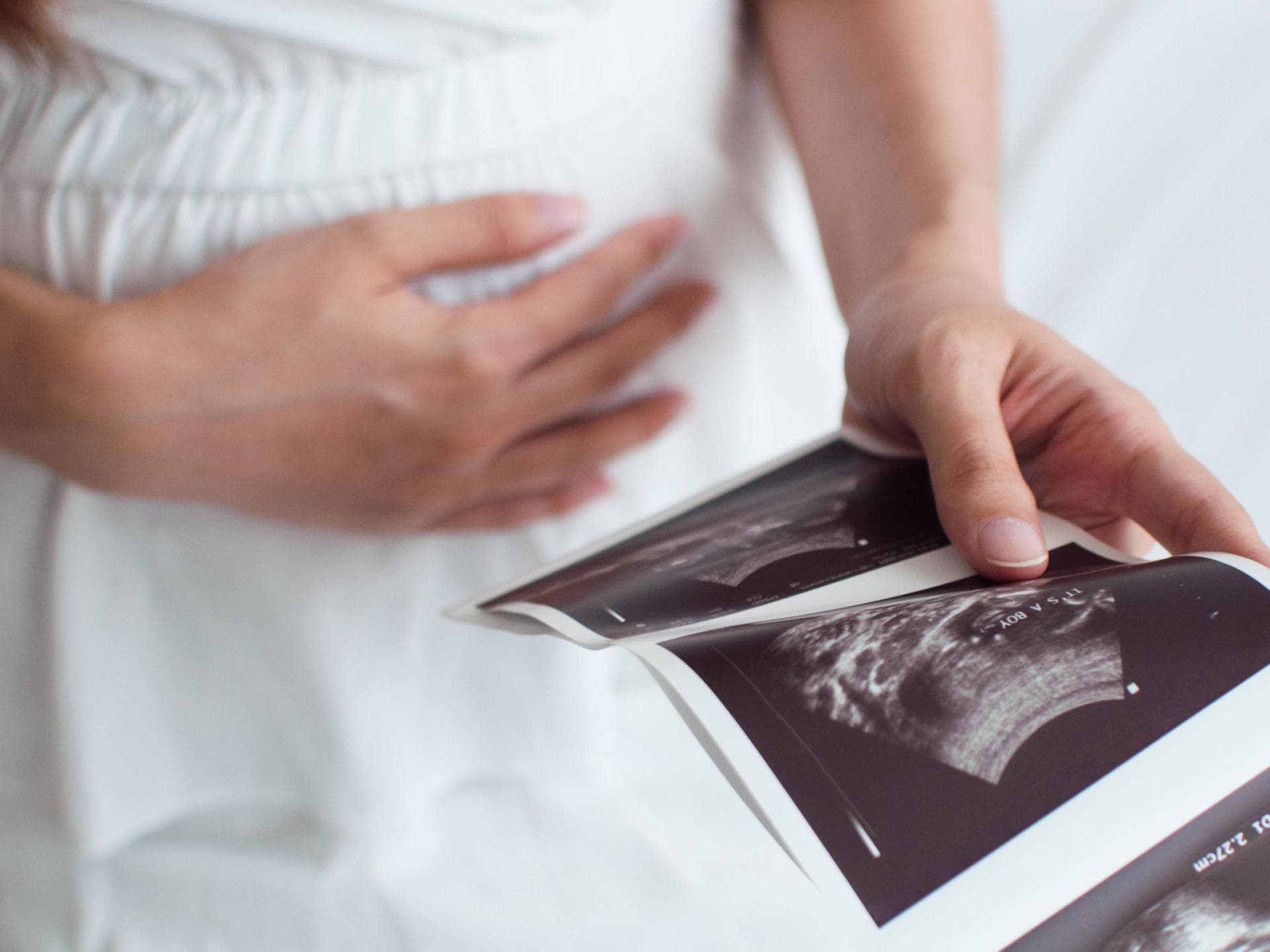 Auch Ultraschallbilder finden in einer Mutterpasshülle Platz. Schwangere Frau mit Ultraschallbildern.