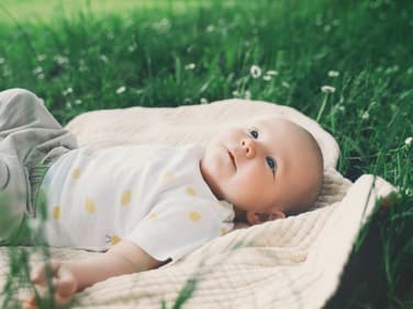 Baby liegt auf einer Wiese.