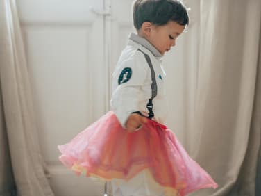 Junge trägt einen rosa Rock.