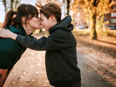 Eine Mutter küsst ihren Teenager-Jungen zärtlich auf die Nase. 