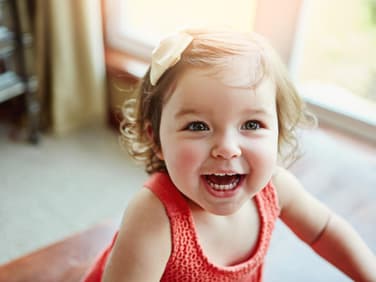 Kleines Baby-Mädchen lacht im hellen Licht der Sonne