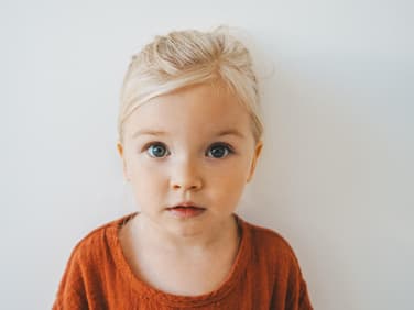 Blondes Mädchen schaut in die Kamera.