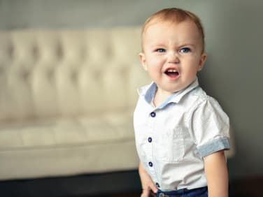Kleiner Baby-Junge rümpft die Nase und schaut keck in die Gegend. 