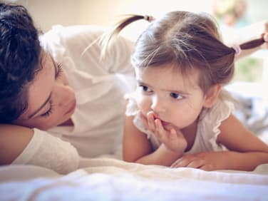 Mutter spricht mit ihrer Tochter im Bett.