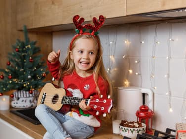 Kleines Mädchen singt mit Gitarre in der Hand ein Nikolauslied.