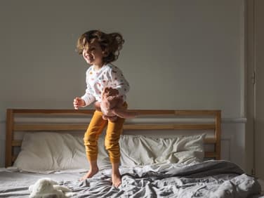 Kleines Mädchen springt auf dem Bett.