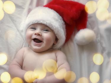 Lachendes Baby mit Weihnachtsmütze.