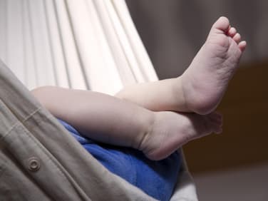 Babyfuß ragt aus der Federwiege.