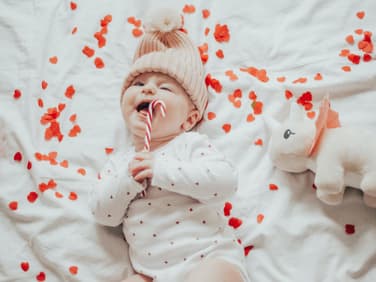 Baby liegt im Bett voller Herzen.