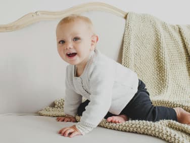 Kleines Mädchen sitzt auf Sofa.