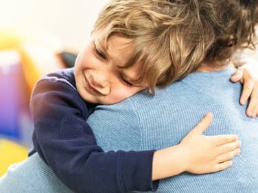 Ein kleiner Junge liegt weinend in den Armen seiner Mutter. 