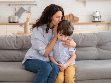 Mutter umarmt Sohn auf dem Sofa.