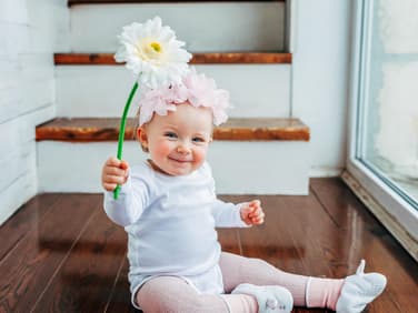 Ein kleines Baby, das eine Blume hält. 