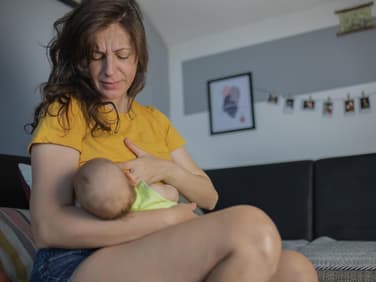 Mutter legt ihr Baby zum Stillen an. 