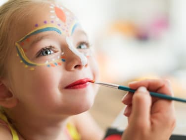 Zauberhaftes Mädchen, das für Karneval geschminkt wird.