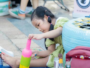 Mädchen bemalt Flasche bunt.
