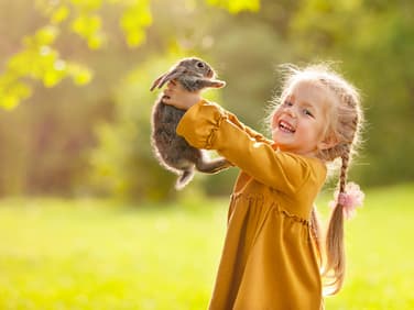 Mädchen hält Hasen hoch.