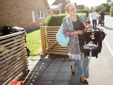 Eine Mutter trägt ihr Baby im Maxi Cosi über die Straße