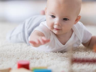 Baby greift nach Bausteinen.