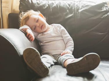 Ein Kleinkind, das auf dem Sofa einschläft.