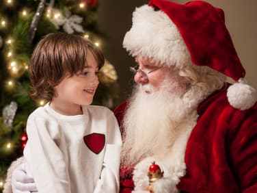 Kind sitzt auf dem Schoß vom Nikolaus oder Weihnachtsmann.