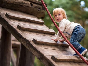 Kleinkind klettert auf Klettergerüst.