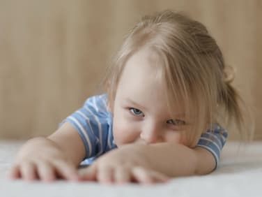 Kleines Mädchen liegt auf dem Boden.