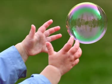 Ein Kind greift nach einer Seifenblase.